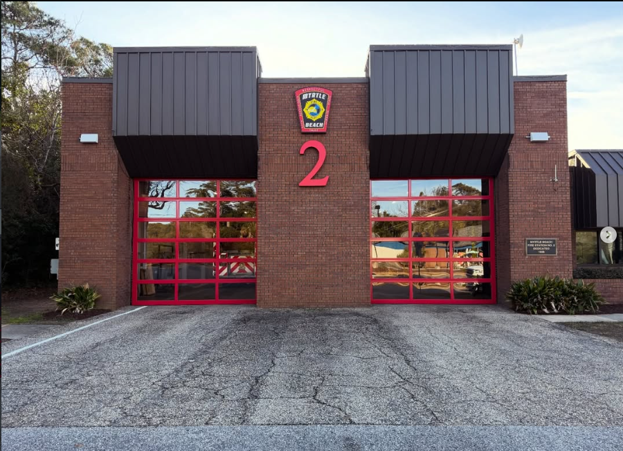 Front facade of Myrtle Beach Fire Station 2 with red-framed glass bay doors and the station number 2